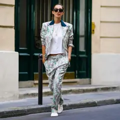Donna con tailleur floreale e scarpe basse cammina per strada, con un'aria disinvolta e chic.