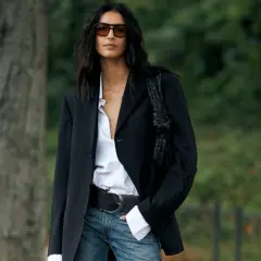Donna con blazer gessato, camicia bianca sbottonata e jeans. Un look chic e casual.