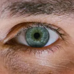 Occhio con iride verde-blu e segni di stanchezza sotto. Scopri come far sparire le occhiaie per uno sguardo più riposato.