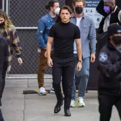 Tom Holland indossa un outfit elegante con scarpe perfette per pantaloni a sigaretta donna, mentre cammina con un gruppo di persone.