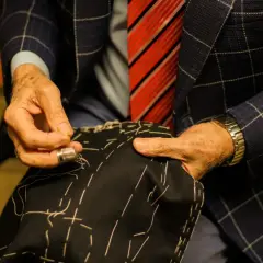 Sarto esperto cuce a mano, mostrando diversi tipi di polsini camicia. Dettagli sartoriali e precisione.