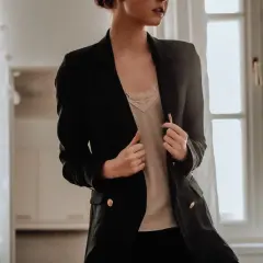 Donna con tailleur nero, indossa una camicetta di pizzo color crema sotto. Un'idea su cosa mettere sotto un tailleur nero.