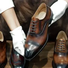 Mani guantate presentano una scarpa stringata marrone lucida, con la linguetta scarpa ben visibile. Altre scarpe eleganti in esposizione.