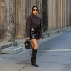 Donna con gonna di pelle e stivali alti neri, un look audace. Perfetto per capire che scarpe abbinare con una gonna di pelle.