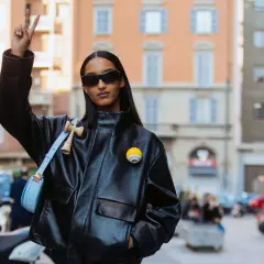 Mona Tougaard, con occhiali da sole e giacca di pelle, fa il segno della pace. Indossa una borsa azzurra e un distintivo giallo.