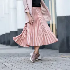Gonna plissettata rosa cipria, un outfit inverno chic con blazer e sneakers.