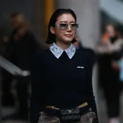 Donna con maglione nero e colletto di camicia bianco decorato con strass, un esempio di diversi tipi di colletto camicia donna.
