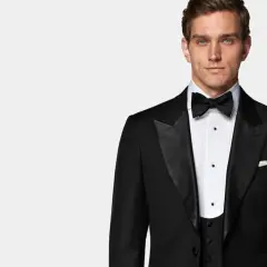 Uomo elegante con smoking e cravatta nera, pronto per un evento speciale.