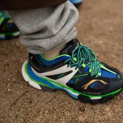 Sneaker Balenciaga con suola chunky, significato di stile audace e comfort. Lacci verdi vivaci su nero, blu e bianco.