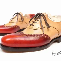 Scarpe Oxford bicolore con tomaia in pelle chiara e inserti rossi. Dettagli traforati e cuciture a vista.