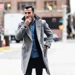 Uomo con giubbotto sopra giacca grigia, in strada.