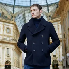 Giovane uomo con un caban blu scuro, un capo che incarna eleganza e calore, passeggia sotto la volta di una galleria storica.
