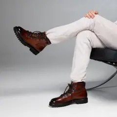 Un uomo con un outfit elegante, composto da pantaloni a coste e giacca chiara, sfoggia un paio di chelsea boots uomo in pelle marrone lucida, perfetti per un look sofisticato.