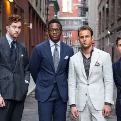 Quattro uomini in abiti eleganti, con un focus sul bavero giacca di ogni completo.