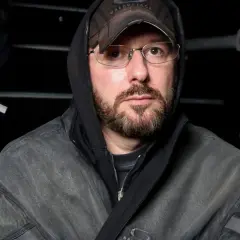 Uomo con cappuccio e cappellino Balenciaga, occhiali e barba, pronto per la sfilata Gucci.