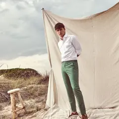 Uomo con pantaloni verdi abbinamento perfetto per un look casual chic sulla spiaggia.