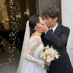Alessandra Mastronardi e il suo sposo si baciano fuori dalla chiesa, tra petali di fiori e un'atmosfera di gioia per il loro matrimonio.