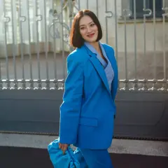 Donna con tailleur blu elettrico, borsa coordinata. Quali scarpe abbinare per un look audace?