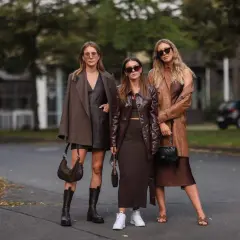 Tre donne con outfit in tonalità marroni e cammello. Un esempio di come abbinare il color cammello con capi in pelle e tessuti fluidi.