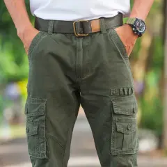 Uomo con outfit composto da pantaloni cargo verdi, cintura in tessuto e orologio sportivo.