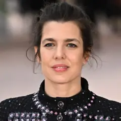 Charlotte Casiraghi, con un'acconciatura raccolta e un abito scuro scintillante, sorride con un'espressione serena.