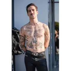 Damiano David, a torso covered in tattoos, poses confidently.