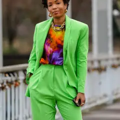Donna con completo verde brillante, maglia tie-dye e collana dorata. Un look che celebra l'armocromia primavera con colori vivaci.