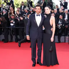 Rebecca Donaldson e il suo compagno sfilano sul red carpet, circondati da fotografi e fan.
