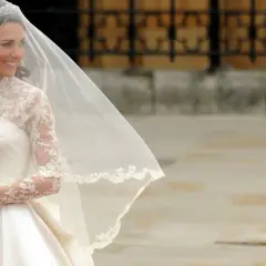 Kate Middleton sposa, radiosa nel suo abito bianco con pizzo e velo, tiene un bouquet di fiori.