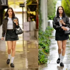 Moda urbana con giacca di pelle, minigonna nera, mocassini e calzini bianchi. La ragazza cammina con un caffè in mano.