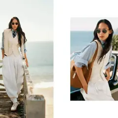 Donna in stile smart casual con pantaloni bianchi ampi, gilet e camicia azzurra, con un tocco di eleganza sulla passerella vista mare.