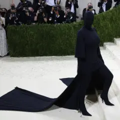 Kim Kardashian al Met Gala, un'apparizione misteriosa in nero totale, con un abito che si estende sul tappeto bianco.