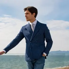 Uomo elegante con abito doppiopetto blu a righe, perfetto come invitato a una cerimonia estiva.
