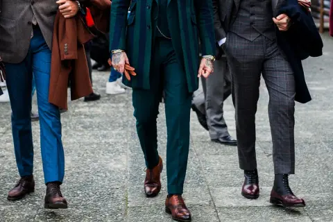 Uomini con abiti eleganti, focus su lunghezza pantalone con mocassino e stivali.