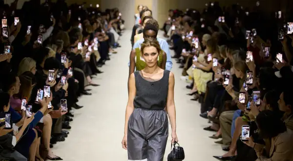 Modella sfila alla Milano Fashion Week 2026, pubblico filma con smartphone.