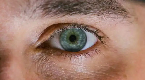 Occhio con iride verde-blu e segni di stanchezza sotto. Scopri come far sparire le occhiaie per uno sguardo più riposato.
