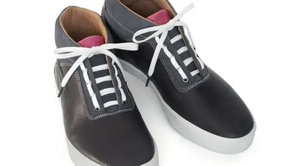 Scarpe sportive nere con lacci bianchi e dettagli grigi. Un esempio di come i lacci scarpe modi possano trasformare un look classico.