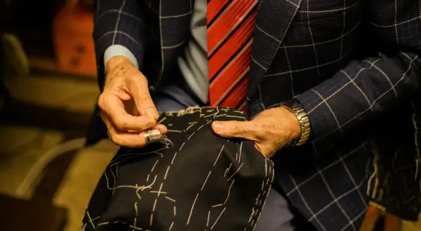 Sarto esperto cuce a mano, mostrando diversi tipi di polsini camicia. Dettagli sartoriali e precisione.