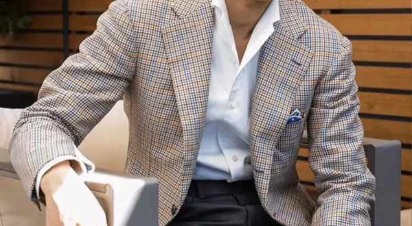 Uomo con giacca a quadri marrone, blu e arancione, camicia bianca e fazzoletto blu. Collezione drop 4.