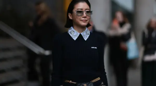 Donna con maglione nero e colletto di camicia bianco decorato con strass, un esempio di diversi tipi di colletto camicia donna.