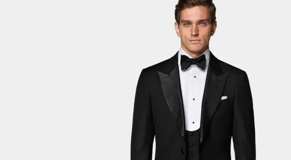 Uomo elegante con smoking e cravatta nera, pronto per un evento speciale.