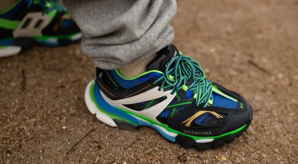 Sneaker Balenciaga con suola chunky, significato di stile audace e comfort. Lacci verdi vivaci su nero, blu e bianco.
