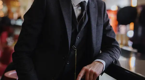 Uomo con completo gessato scuro, gilet e cravatta, un vero esempio di stile italiano.