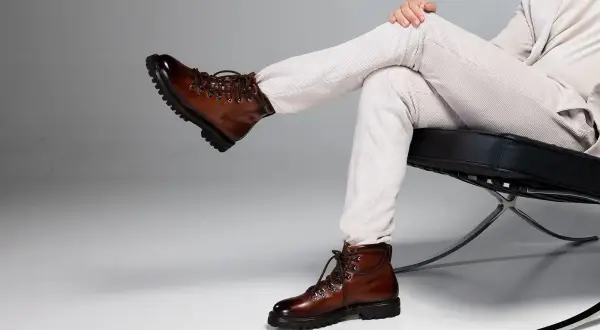 Un uomo con un outfit elegante, composto da pantaloni a coste e giacca chiara, sfoggia un paio di chelsea boots uomo in pelle marrone lucida, perfetti per un look sofisticato.