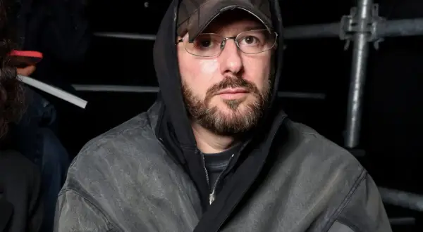 Uomo con cappuccio e cappellino Balenciaga, occhiali e barba, pronto per la sfilata Gucci.