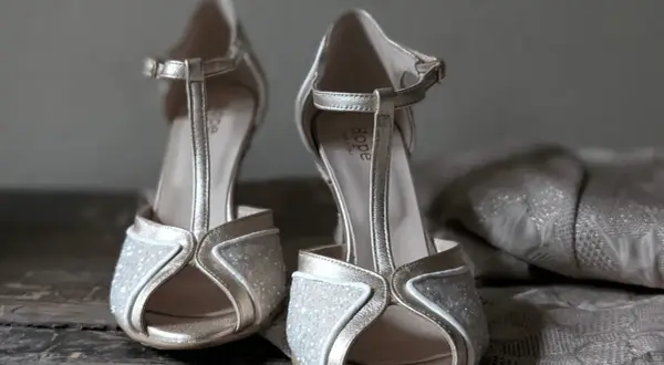 Scarpe dorate con glitter e cinturino a T, perfette da abbinare a un abito in pizzo per un look da cerimonia.