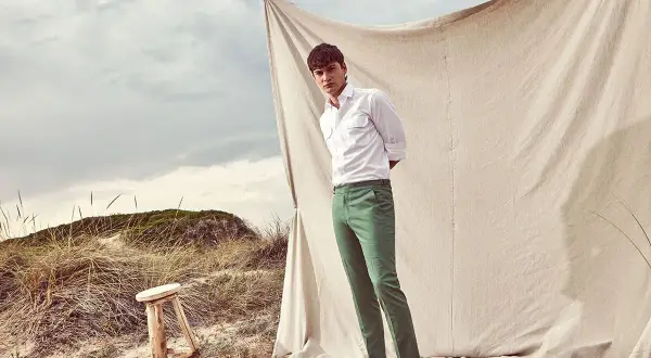 Uomo con pantaloni verdi abbinamento perfetto per un look casual chic sulla spiaggia.