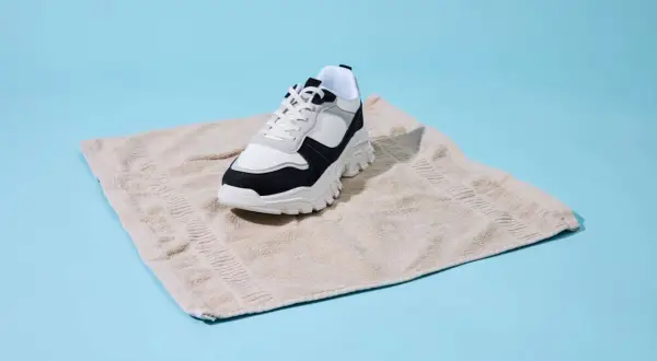 Sneaker bianco e nero su asciugamano beige, un metodo per asciugare scarpe bagnate dentro.