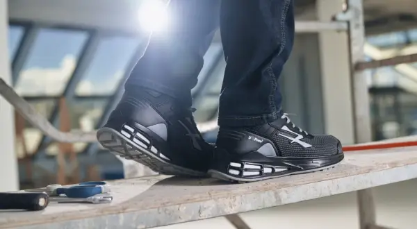 Scarpe guida U Power nere, con dettagli grigi e bianchi, indossate su un ponteggio. Perfette per chi lavora in cantiere.