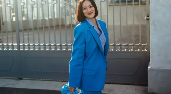 Donna con tailleur blu elettrico, borsa coordinata. Quali scarpe abbinare per un look audace?